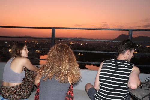 乌代浦Bunkyard Hostel的三人组坐在阳台上欣赏日落
