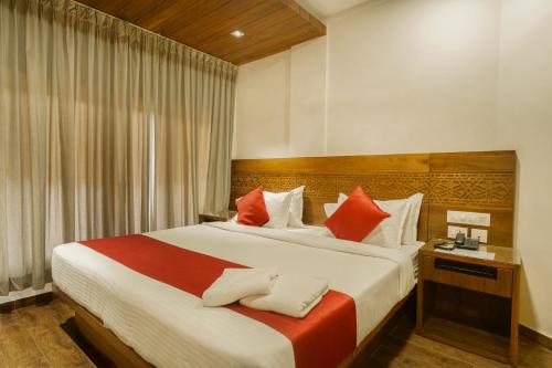 科泽科德KINGS CALICUT的一间卧室配有一张带红色和白色枕头的大床