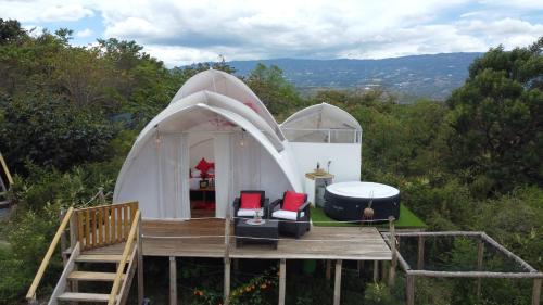 莱瓦镇Origen Glamping en Villa de Leyva的大型白色圆顶帐篷 - 带甲板和椅子