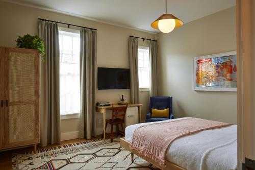 金斯顿Hotel Kinsley的一间卧室配有一张床、一张书桌和一台电视。