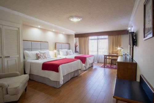 马特瓦拉Hotel del Parque的酒店客房,配有两张带红色床单的床