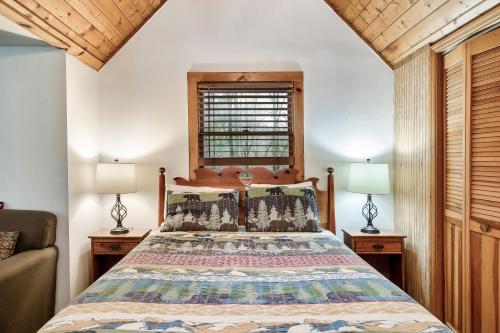 加特林堡Wolf Run Gatlinburg Location Log Cabin Hot Tub的一间卧室配有一张床、两盏灯和一个窗户。