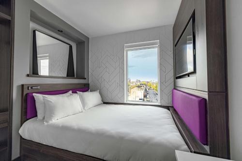 伦敦YOTEL London Shoreditch的一间卧室设有一张大床和两个窗户
