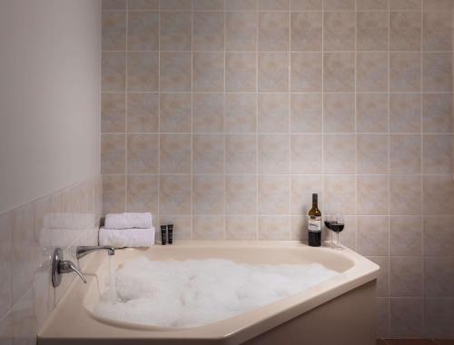 罗托鲁瓦Arawa Park Hotel, Independent Collection by EVT的白色浴缸及一瓶葡萄酒