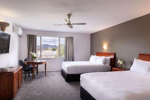 罗托鲁瓦Arawa Park Hotel, Independent Collection by EVT的酒店客房设有两张床、一张桌子和一个窗户。