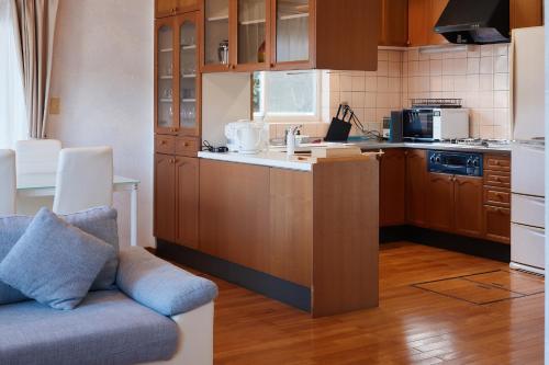 壹岐市ritomaru house iki ashibe的一个带木制橱柜的厨房和一个沙发