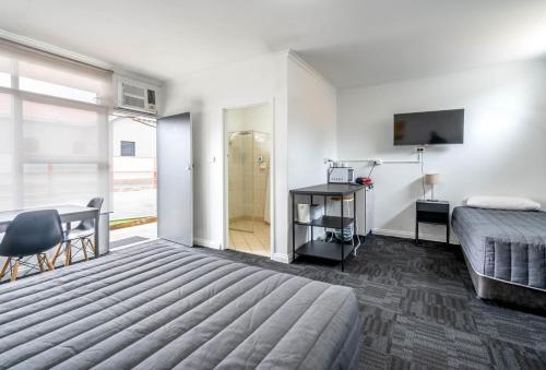 阿德莱德市西汽车旅馆的一间卧室配有一张床、一张书桌和一台电视