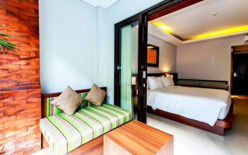 登巴萨Grand Mirah Boutique Hotel的一间卧室配有一张床和一个沙发