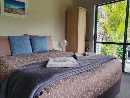 Kaihu贝壳杉海岸十大假日公园 的一间卧室配有一张大床和毛巾