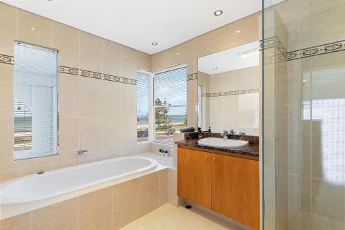 曼哲拉Beachfront Family Favourite Home with Pool & Views的带浴缸和盥洗盆的浴室