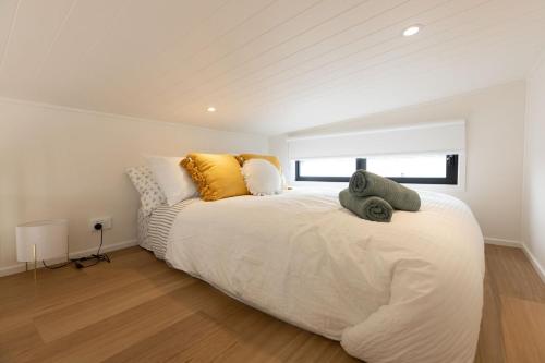 赫斯基森Husky Tiny Home by Experience Jervis Bay的卧室配有一张带黄色枕头的大型白色床。