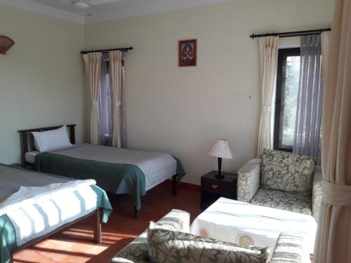 加德满都Drala Resort Nepal的一间卧室设有两张床、一把椅子和一个窗户。