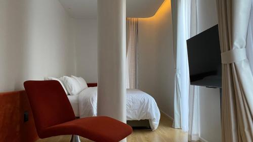 清迈The Sayla hotel(Baan Sayla)的一间卧室配有一张床和一张红色椅子