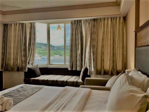 普塔帕蒂Sai Towers的一间卧室配有一张床、一张沙发和一个窗口