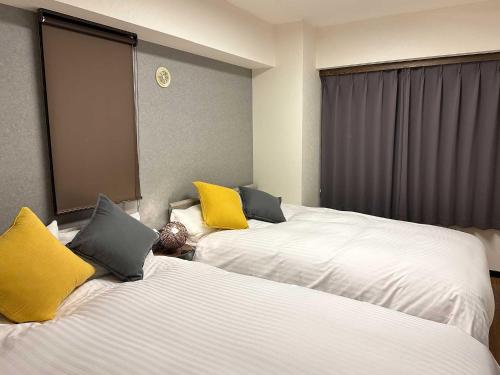 札幌LIT’S INN Sapporo的酒店客房 - 带两张带黄色枕头的床