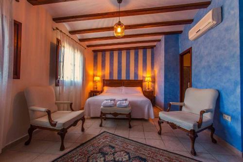 BenialiBoutique hotel El Capricho的一间卧室配有一张床和两把椅子