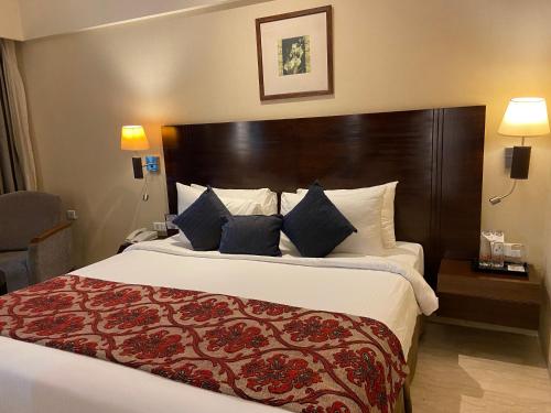 纳威孟买Fortune Select Exotica, Navi Mumbai - Member ITC's Hotel Group的一间卧室配有一张大床和大型木制床头板