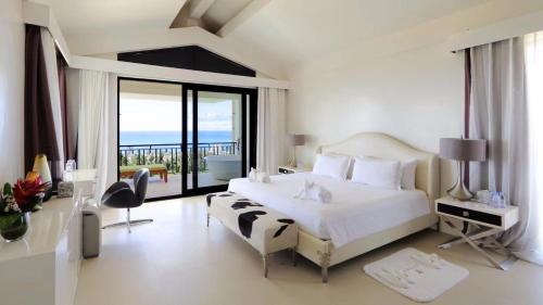 加拉班Navy Hill Resort的一间带一张白色大床的卧室和一个阳台