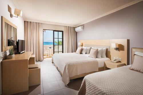 卡尔扎迈纳Porto Bello Beach Hotel的酒店客房设有两张床和电视。