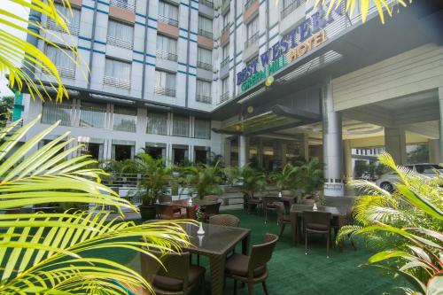 仰光Best Western Green Hill Hotel的酒店庭院设有桌椅和植物