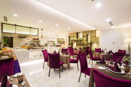 仰光Best Western Chinatown Hotel的一间设有紫色桌椅的餐厅和一间厨房