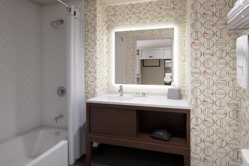 圣路易斯Holiday Inn St Louis - Creve Coeur的浴室配有盥洗盆、镜子和浴缸