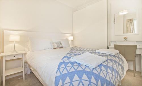 阿伯蒂费Beautiful Aberdovey Seafront Apartment 2的白色卧室配有蓝色和白色的床和书桌
