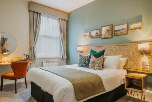 马特洛克Grouse & Claret, Matlock by Marston's Inns的一间卧室配有一张床、一张书桌和一个窗户。