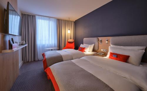杜塞尔多夫杜塞尔多夫城北快捷假日酒店的酒店客房,设有两张床和一张红色椅子
