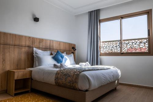 达赫拉Karam City Hotel的一间卧室配有一张带木制床头板的床和窗户。