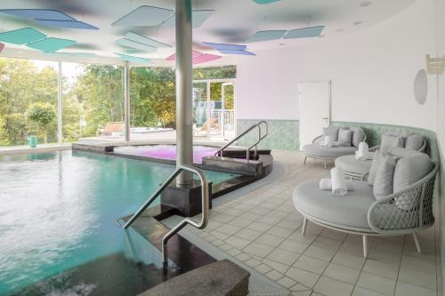 英格堡Hotel Waldegg - Adults only的一个带两把椅子和一张桌子的游泳池以及一个游泳池