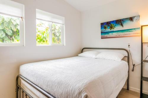 帕霍阿Puni Mauka B 31 plus day rental的一间卧室配有一张带白色床单的床和两个窗户。