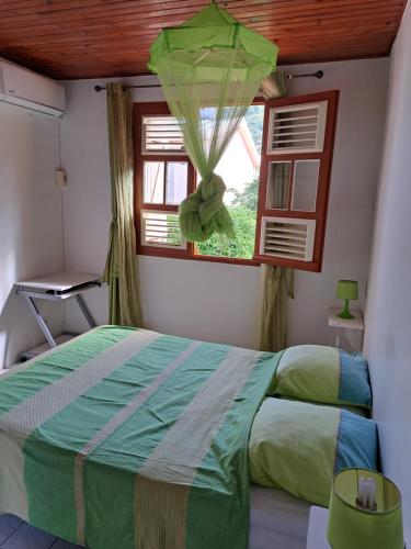 莱昂斯-达赫雷MAISON de VACANCES ANSES D'ARLET的一间卧室设有一张绿色的床和一个窗户。