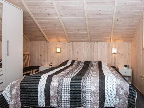 安斯艾厄Holiday home Ansager XLIII的卧室配有一张床铺,位于带木墙的房间内