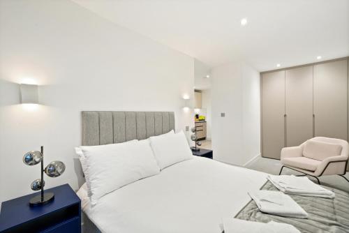 伦敦Executive 1 & 2 Bed Apartments in heart of London FREE WIFI by City Stay Aparts London的白色卧室配有床和椅子