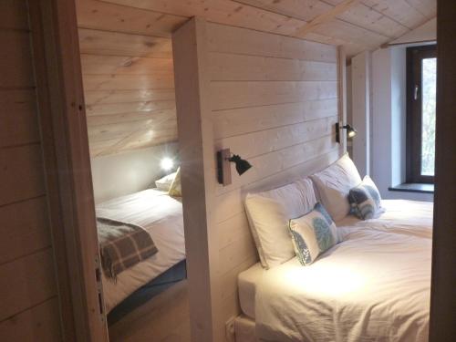 谷雪维尔Appartement Le Hibou的一间带两张床铺的卧室,位于带木墙的房间内