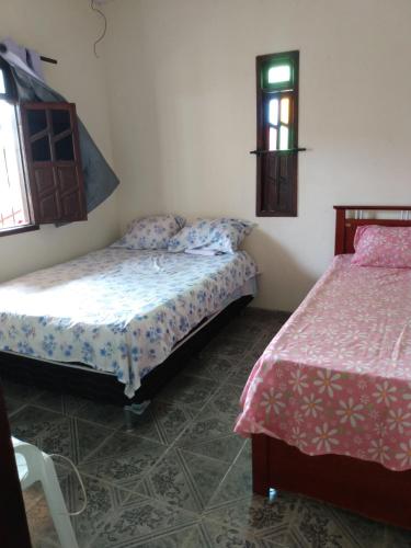 卡马萨里Refúgio sossego (casa de campo)的一间卧室设有两张床和窗户。