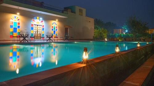 KhilchīpurAnantvan Ranthambore By ShriGo Hotels的夜间在房子前面的游泳池