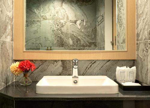 清莱Sann Hotel的浴室水槽,配有镜子和花瓶