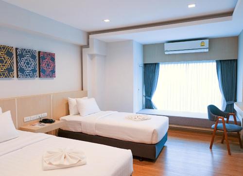 清莱Sann Hotel的酒店客房设有两张床和窗户。