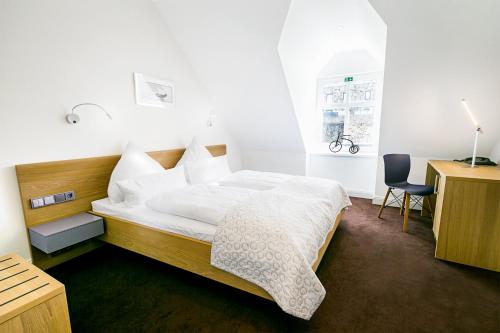 Burgbrohl布尔格布罗尔施劳斯酒店的一间卧室配有一张床、一张桌子和一把椅子