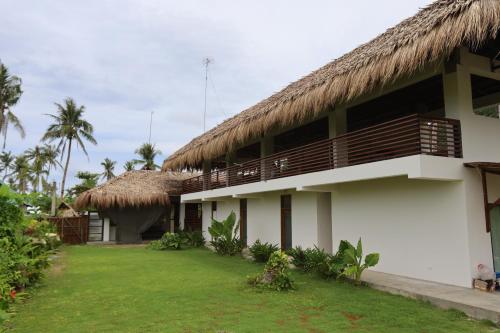 San IsidroLaFinca Hostel Siargao的茅草屋顶和庭院的建筑