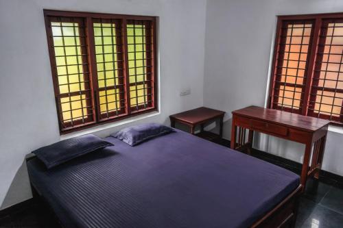 瓦尔卡拉Secret Paradise的一间卧室配有一张床、一张书桌和两个窗户。