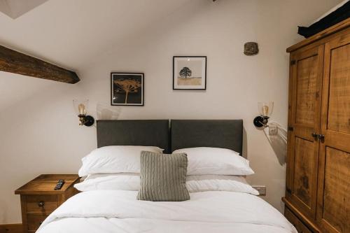 WirksworthFryers Cottage - Beautiful 2 bedroom Town & Country Cottage on edge of Peak District的一间卧室配有一张带白色床单和木制橱柜的床。