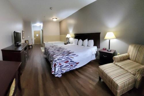 米德兰Red Roof Inn & Suites Midland的酒店客房设有一张大床和一张沙发。