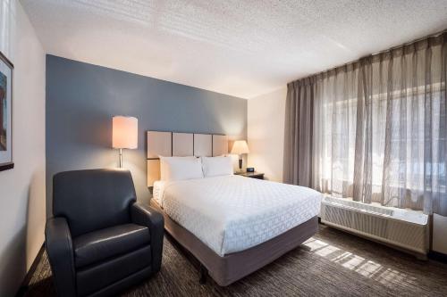 席勒公园Sonesta Simply Suites Chicago O'Hare Airport的配有一张床和一把椅子的酒店客房