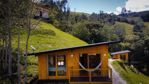 帕斯托Villa De Los Sueños的小木屋,后面是一座草木山丘