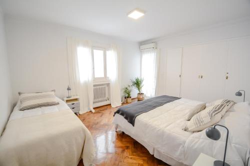 门多萨Anden Espejo的卧室设有两张床,拥有白色的墙壁和木地板