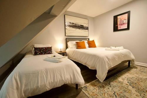 沃尔瑟姆Entire Cozy House near Moody St, Bentley, Brandeis的一间卧室配有两张带白色床单和橙色枕头的床。
