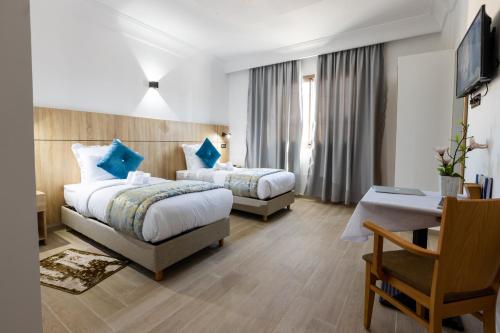 达赫拉Karam City Hotel的酒店客房配有两张床和一张书桌